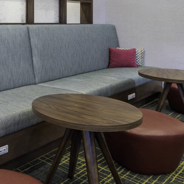Upholstered banquette with walnut occasional tables and leather ottomans.