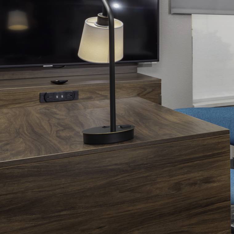 Table lamp on a walnut casegood with an integrated power and USB module.