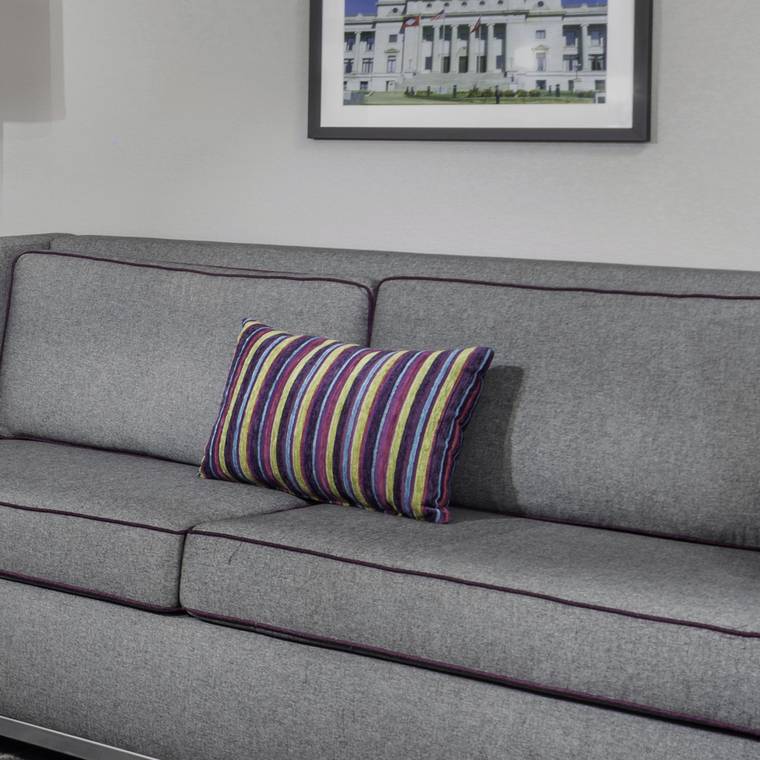 A striped throw pillow set on the sleeper sofa in a finished guestroom at Conway.
