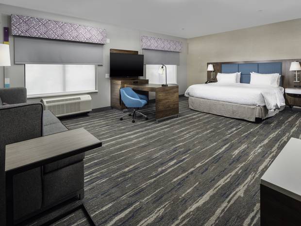 King guestroom at Conway: bed and headboard, casegoods, desk, task chair, lamps, window treatments and patterned carpet.