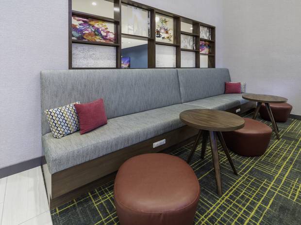 Upholstered banquette, walnut occasional tables, leather ottomans and a shadow-box art wall at Conway.